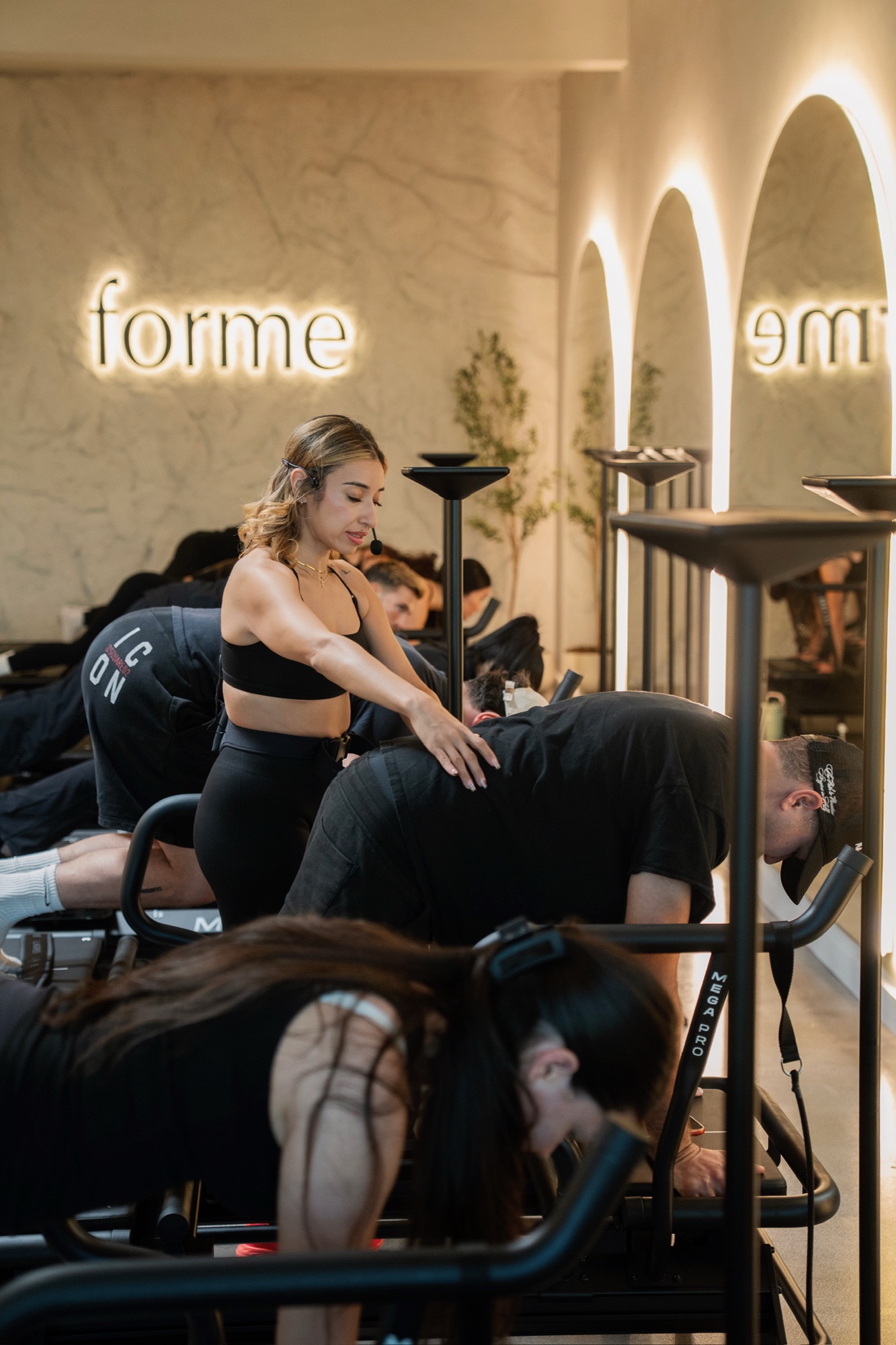 Lagree Master Trainer Claudia Canales adjusting a student's form during certification at Forme Lagree studio in Burbank, California
